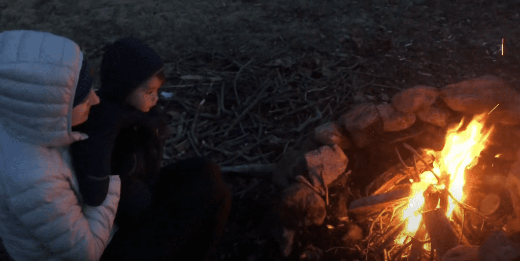 Baby bei Wanderung neben Lagerfeuer